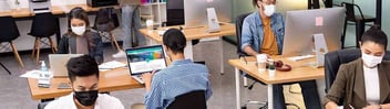 Office workers sitting at desks wearing face masks