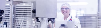 Food technician standing over machine in food factory